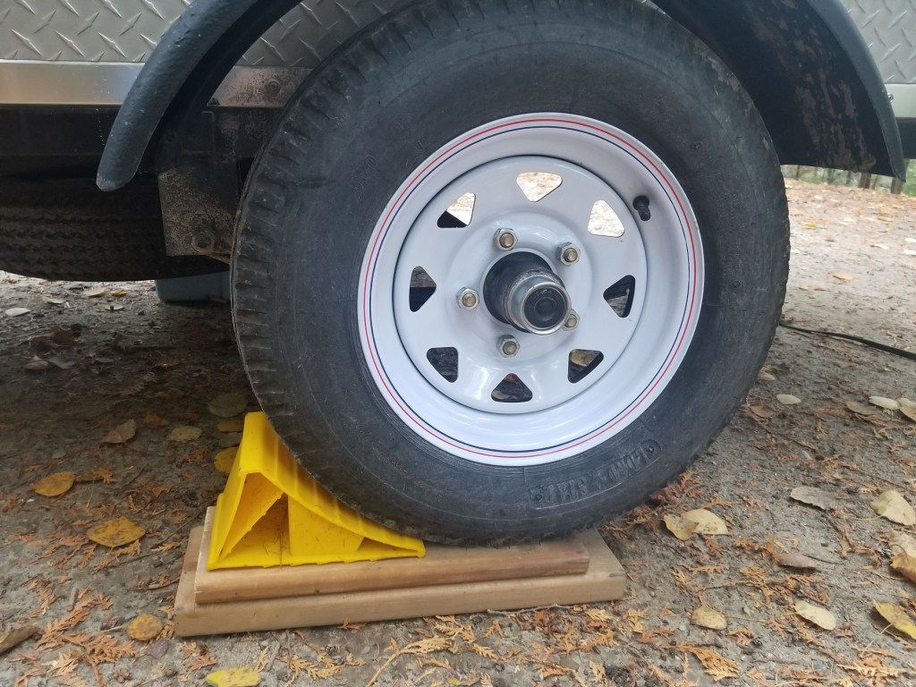 wheel of Teardrop trailer, with planks beneath and a chock in place