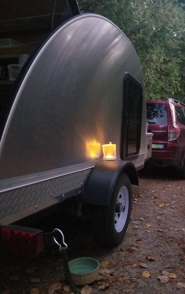 Teardrop trailer at dusk, with illuminated battery-powered candle.