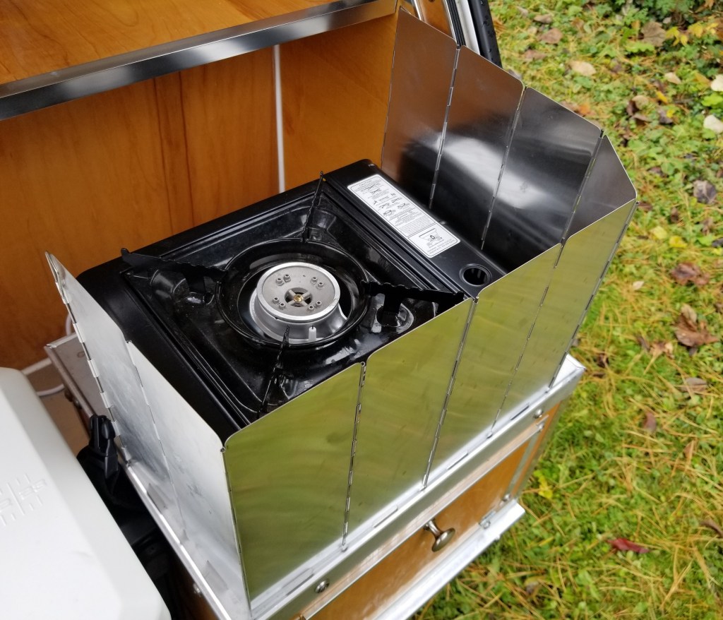 camp stove, shielded on 3 sides by folding aluminum shield