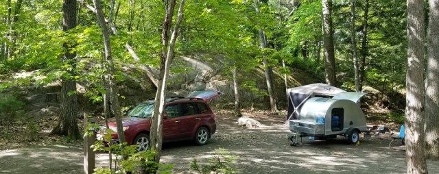 wooded campsite, with teardrop trailer, pop-up shelter, and pulling vehicle shown