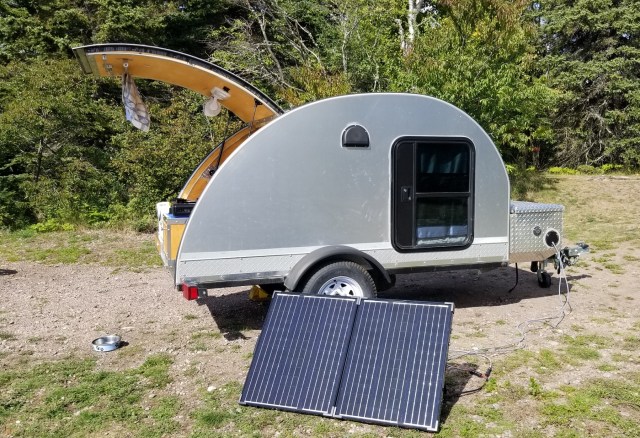 teardrop trailer with hatch open and solar panel in foreground