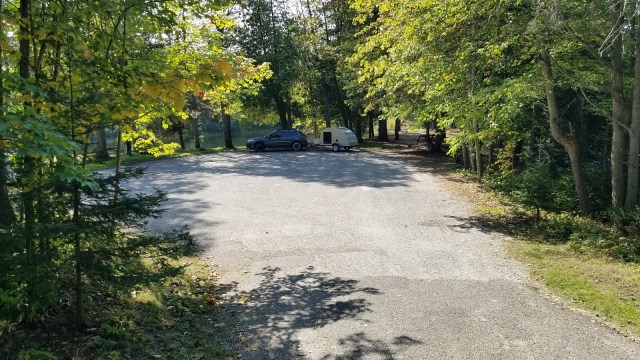 teardrop trailer parked in rustic area near river
