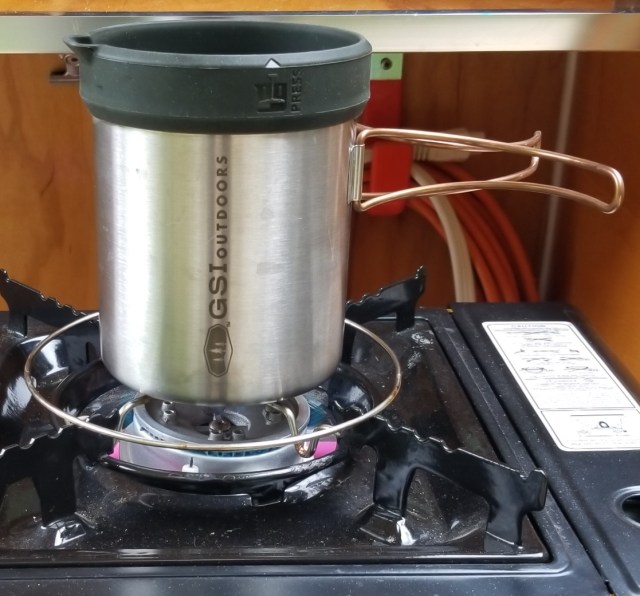 coffee press pot atop camp stove