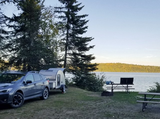 teardrop trailer camped by lakefront in late afternoon sun