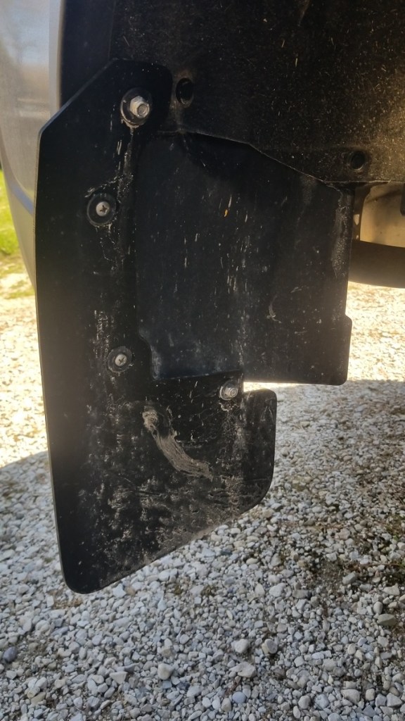 Mud flap, mounted on vehicle, with wheel removed.